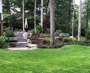 finished backyard stone patio with floral landscaping