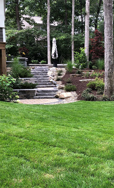 finished backyard stone patio with floral landscaping